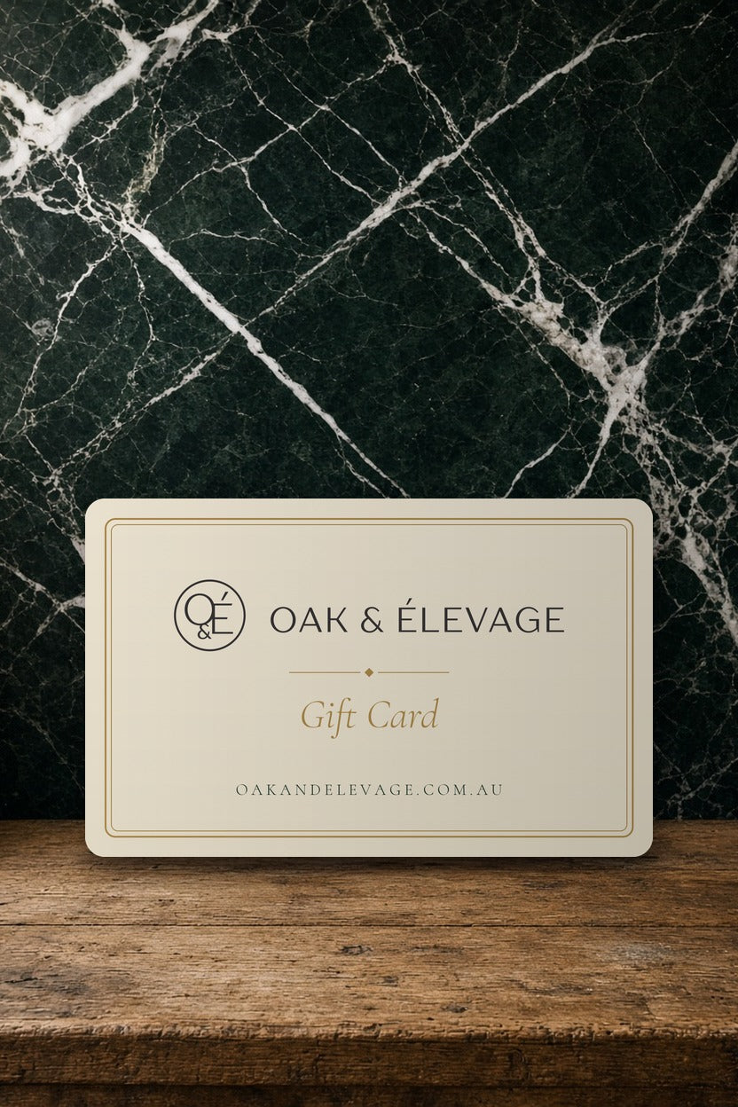 Oak & Élevage Gift Card, ivory and gold card on an oak bench against green marble